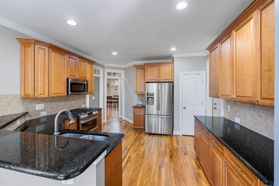 Spacious modern kitchen featuring granite countertops, wooden cabinets, and stainless steel appliances